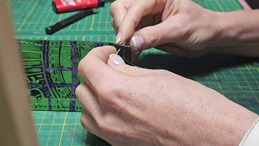 Hands stitching a handmade leather wallet with needle and thread - AG Design, Arad, Romania