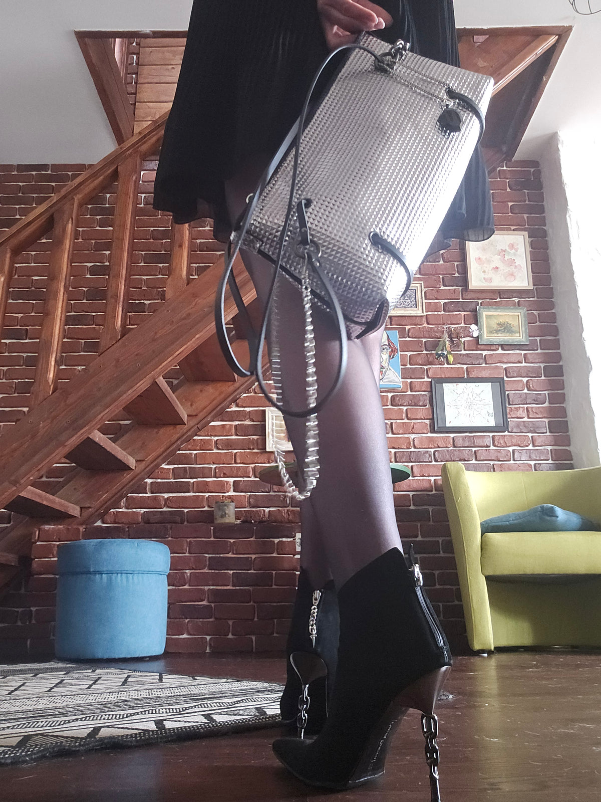 Handmade silver textured leather crossbody bag carried by hand in a brick-walled studio beside a wooden staircase - AG Design, Arad, Romania