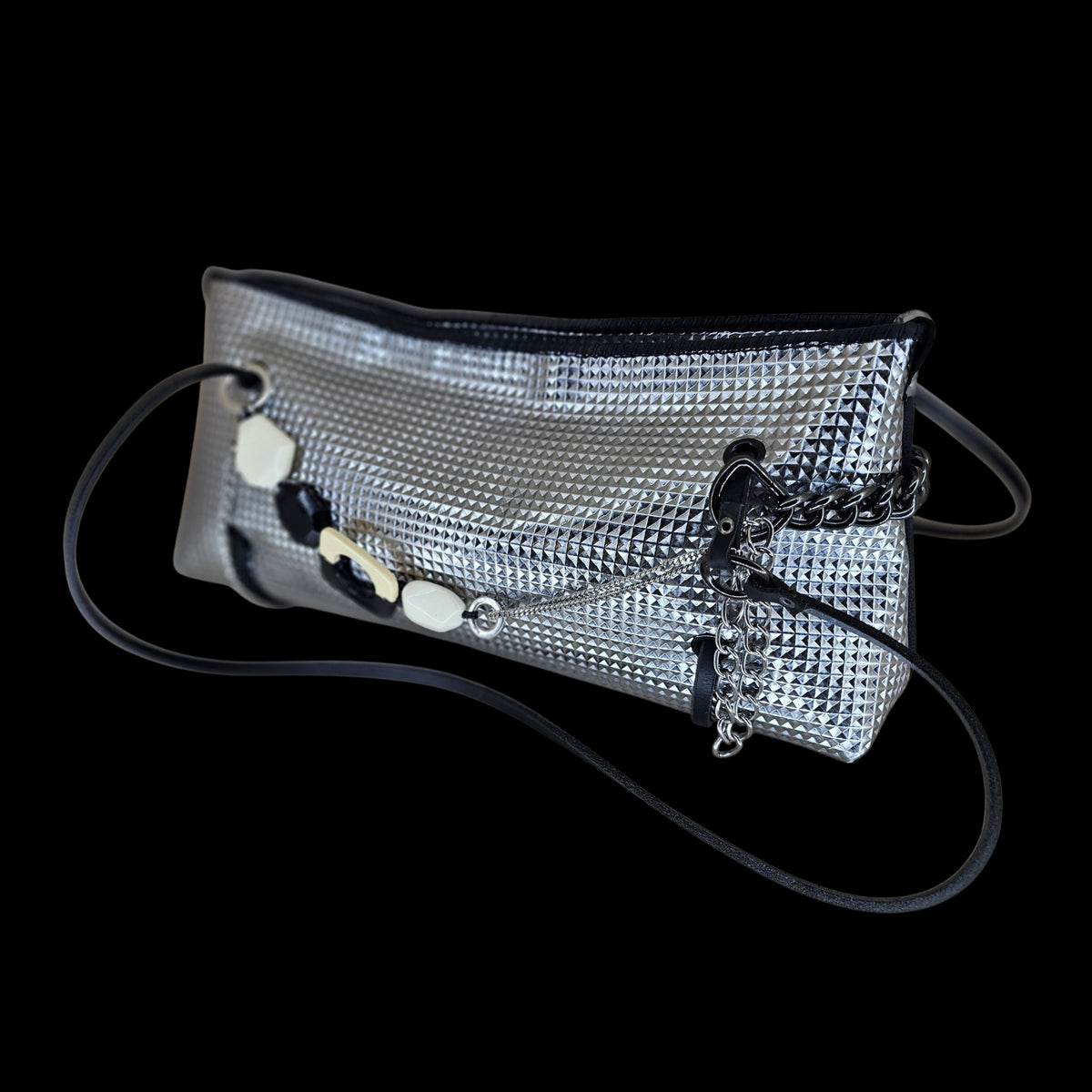 Silver pyramid-textured leather crossbody bag with dark chain and black leather strap, seen at an angle on black - AG Design, Arad, Romania