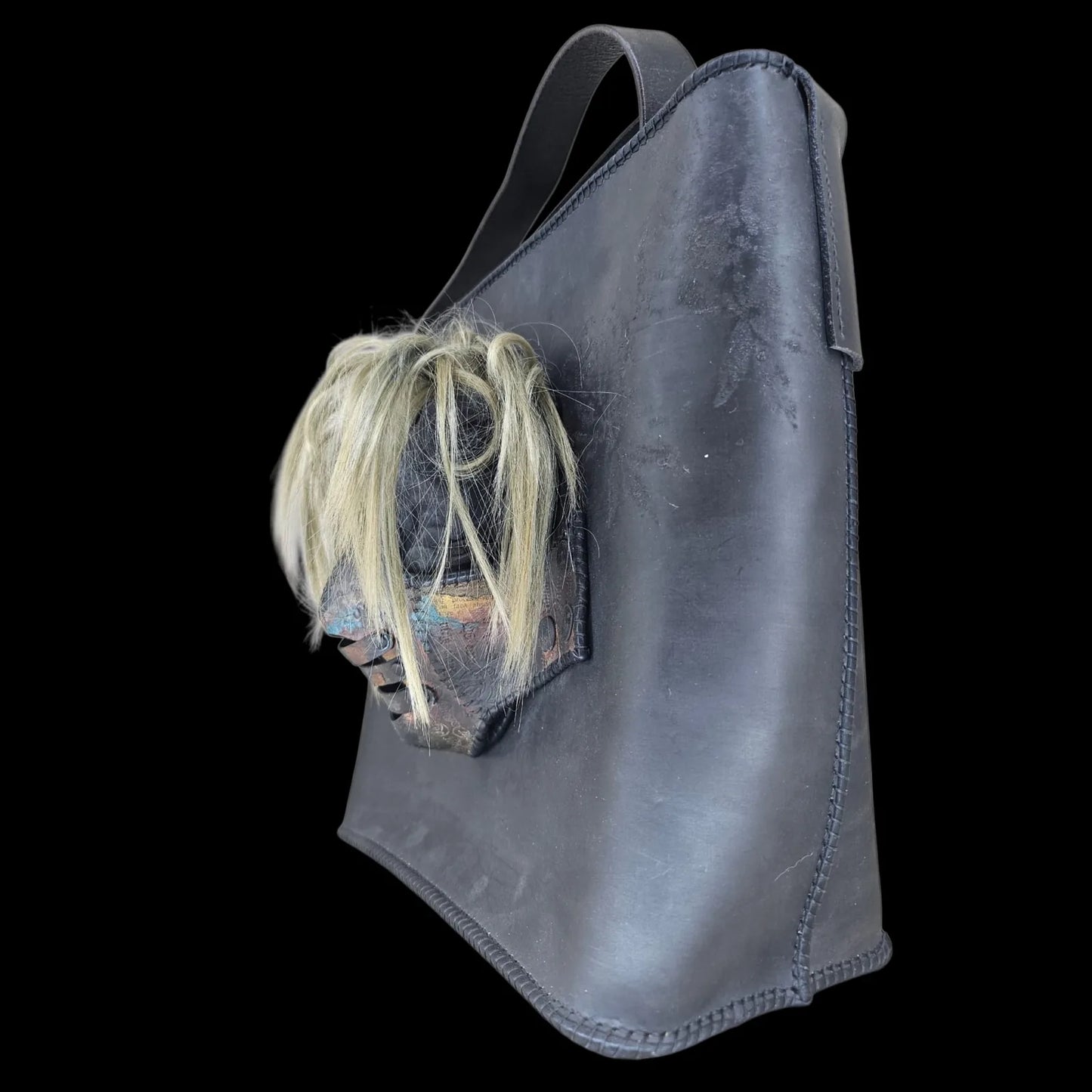 Handmade black leather shoulder bag with an attached 3D sculptural leather mask with metallic and hair-like textures - AG Design, Arad, Romania