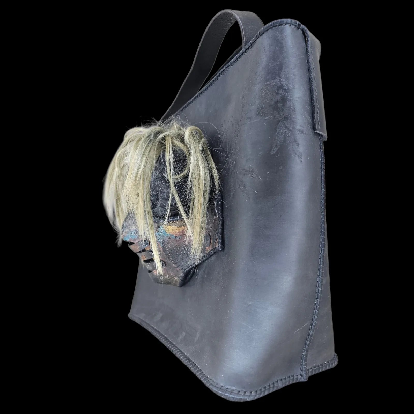 Handmade black leather shoulder bag with an attached 3D sculptural leather mask with metallic and hair-like textures - AG Design, Arad, Romania