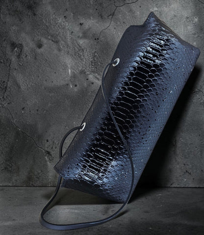 Black snake-embossed leather shoulder bag with slender fixed leather straps through metal eyelets, on a black background - AG Design, Arad, Romania