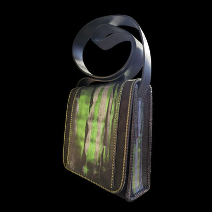 Three-quarter view of a hand-painted black leather shoulder bag with green strokes and a looped leather strap - AG Design, Arad, Romania