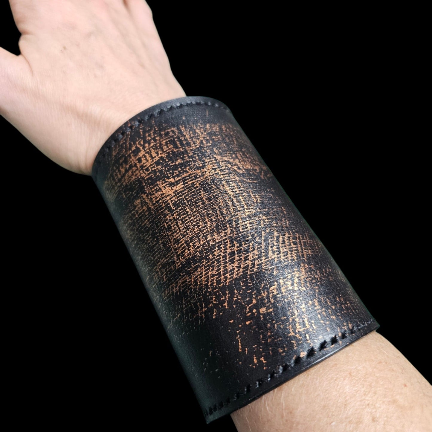 Handmade black leather cuff wallet worn on the wrist, seen from the side, with copper patina and hand-stitched edges - AG Design, Arad, Romania