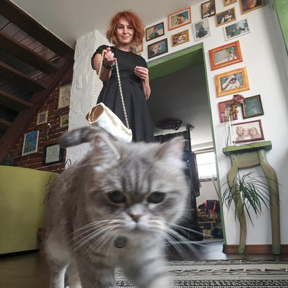 Alexandra holding the white and gold leather barrel bag while a grey cat walks toward the camera - AG Design, Arad, Romania
