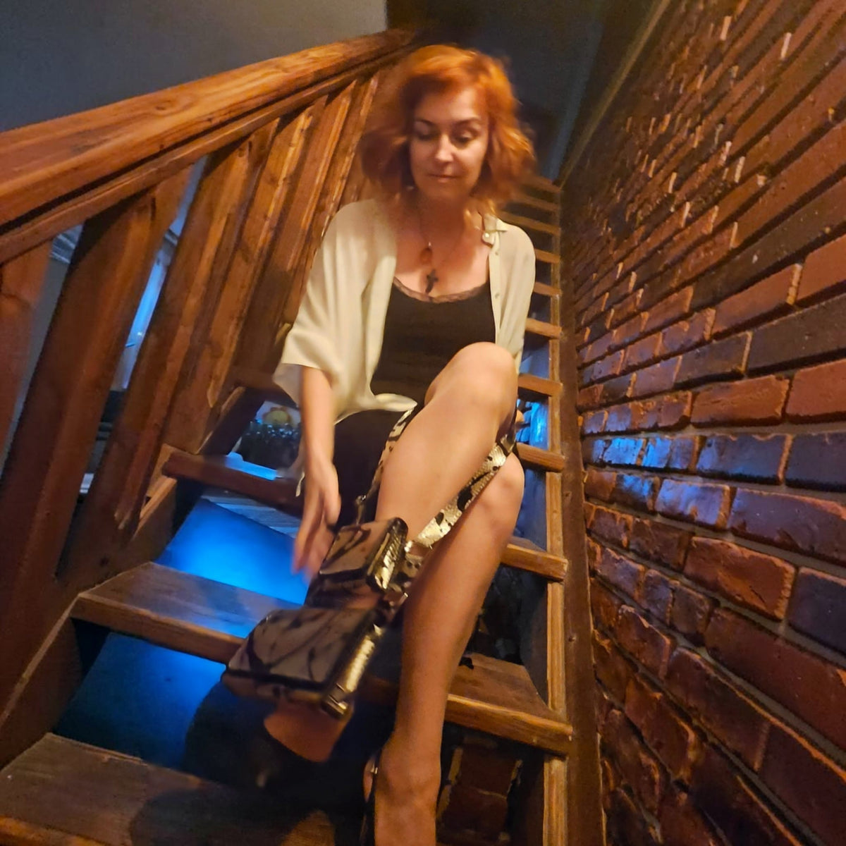 Alexandra holding a handmade gold leather crossbody bag with two pouches on the workshop stairs - AG Design, Arad, Romania