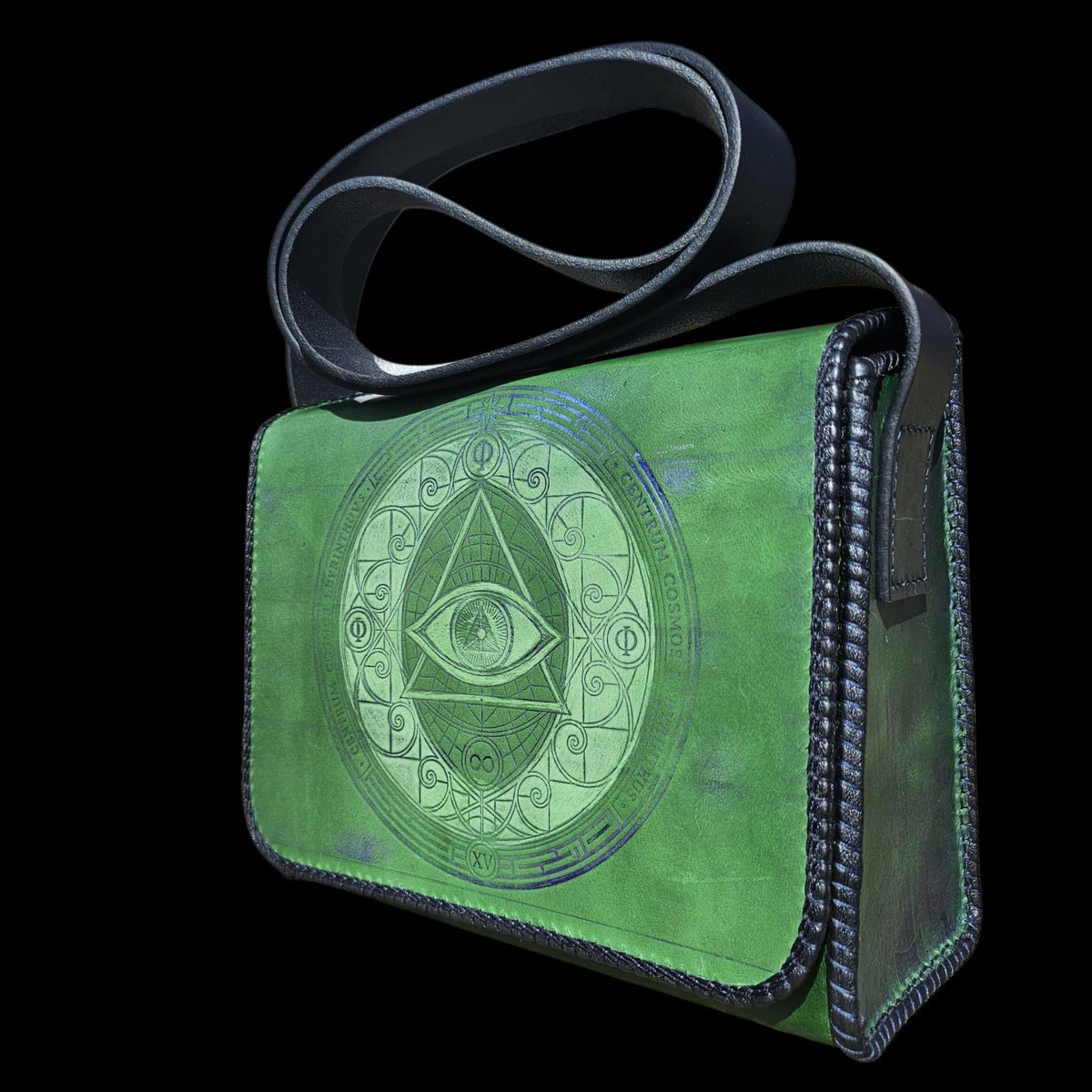 Three-quarter view of a handmade green leather crossbody bag with navy laced edges and a blue-embossed eye in a triangle - AG Design, Arad, Romania